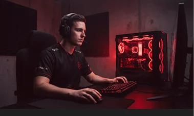 Un giocatore professionista con cuffie da gaming concentrato davanti al computer, con un case per PC illuminato da luci LED rosse sulla scrivania.